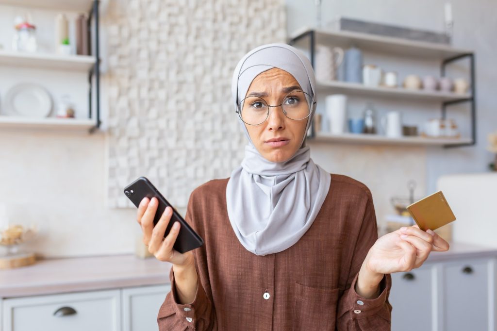 Upset young muslim woman wearing hijab feeling frustration and problems with credit card account