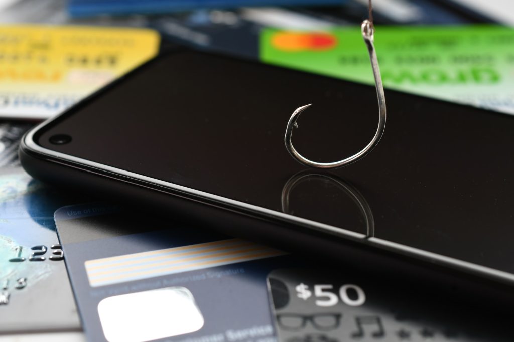 Phishing phone call scams vishing - concept. Cellphone with fishing hook, credit cards & gift cards